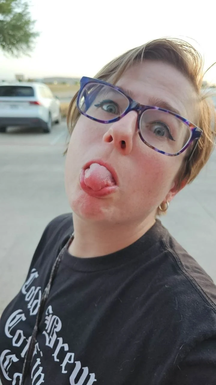 Alannah in purple glasses, pulling a playful face outdoors